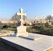 Памятник в форме креста, выполнен из серого мрамора.